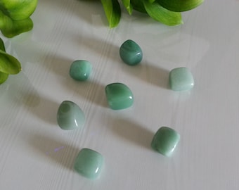May include: Eight smooth, light green tumbled stones arranged in a pattern on a white surface.