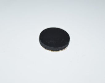 May include: A black round furniture pad with a sticky adhesive backing.
