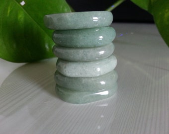 May include: A stack of six smooth, light green jade rings. The rings are stacked on top of each other, with the largest ring at the bottom and the smallest ring at the top.