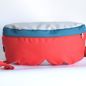 Plain red cordura fanny pack with grey top and teal flap.