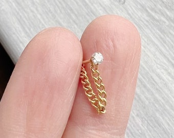 May include: A gold chain earring with a single clear gemstone at the top.
