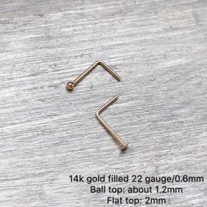 Puede incluir: Dos anillos de nariz de oro, uno con una parte superior redonda y otro con una parte superior plana. 14 quilates de oro relleno, calibre 22/0,6 mm. Parte superior redonda: aproximadamente 1,2 mm. Parte superior plana: 2 mm.