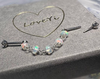 May include: A silver body jewelry piece with a chain and five opal beads. The jewelry is in a gray box with a heart shape and the text "LoveYi" inside the heart.