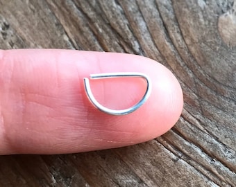 May include: A small, silver, half-circle jump ring. The ring is about the size of a fingernail.