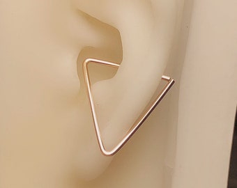 Puede incluir: Un aro para la oreja en forma de triángulo de oro rosa. El aro está hecho de metal fino y está diseñado para ser usado en la parte superior de la oreja.