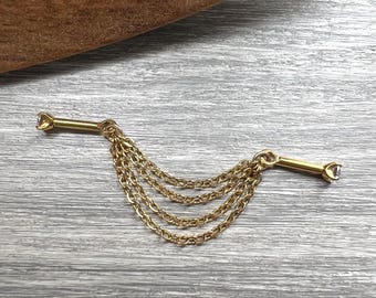 May include: A gold-toned tie chain with a bar on each end, each with a small, clear gem. Four delicate chains hang between the bars. The tie chain is displayed on a gray wooden surface.
