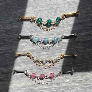 May include: Four decorative collar pins with beaded accents. The pins feature gold and silver-toned metal bars with decorative ends. Each pin has a chain with three beads in green, blue, clear, and pink.
