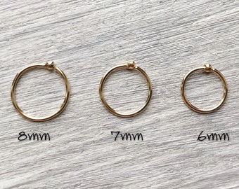 May include: Three gold hoop earrings with a small bead on the closure. The hoops are 8mm, 7mm, and 6mm in diameter.