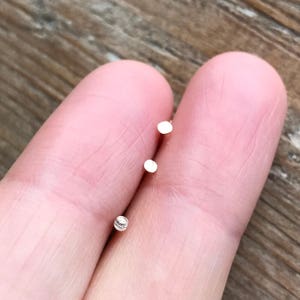 May include: Three silver nose studs, two are round and one is a small ball.
