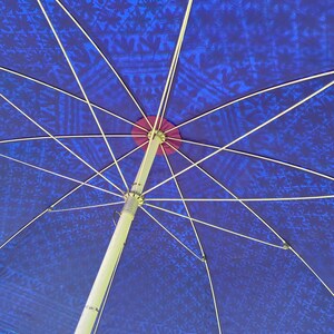 May include: A blue and white patterned umbrella with a silver metal frame. The umbrella is open and the underside of the canopy is visible.