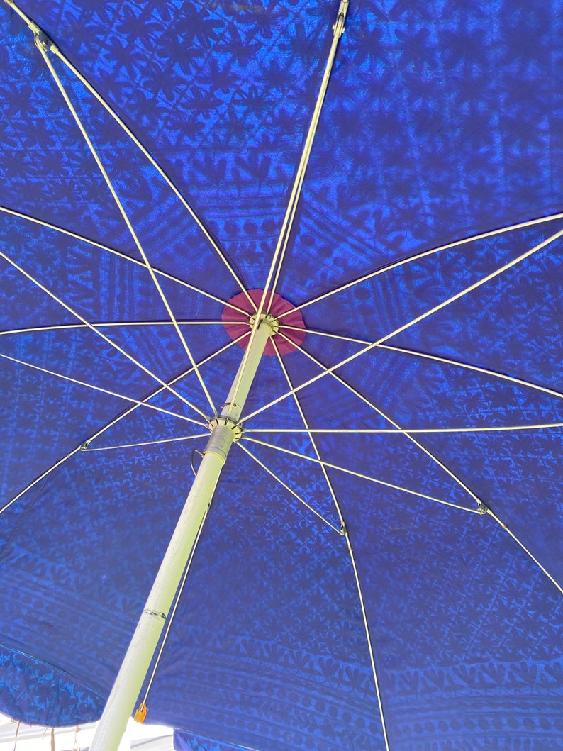 May include: A blue and white patterned umbrella with a silver metal frame. The umbrella is open and the underside of the canopy is visible.