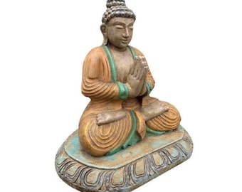 Può includere: Una piccola statua di legno intagliata a mano di un Buddha in meditazione. La statua è dipinta in tonalità di marrone, verde e oro. Il Buddha è seduto in posizione di loto con le mani in grembo. La statua è seduta su una base circolare con un design decorativo.