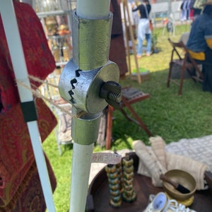 May include: A silver metal connector with a threaded screw, connecting two white poles. The connector has a serrated edge and is labeled "MADE IN CHINA".
