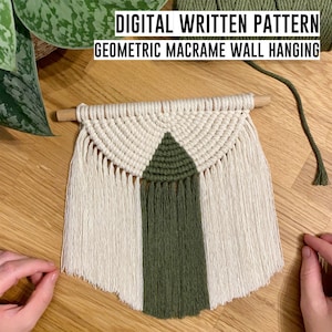 May include: A white and green geometric macrame wall hanging with a wooden dowel at the top. The macrame is made with a knotting technique and has a fringe at the bottom. "DIGITAL WRITTEN PATTERN GEOMETRIC MACRAME WALL HANGING" is written in black text at the top of the image.