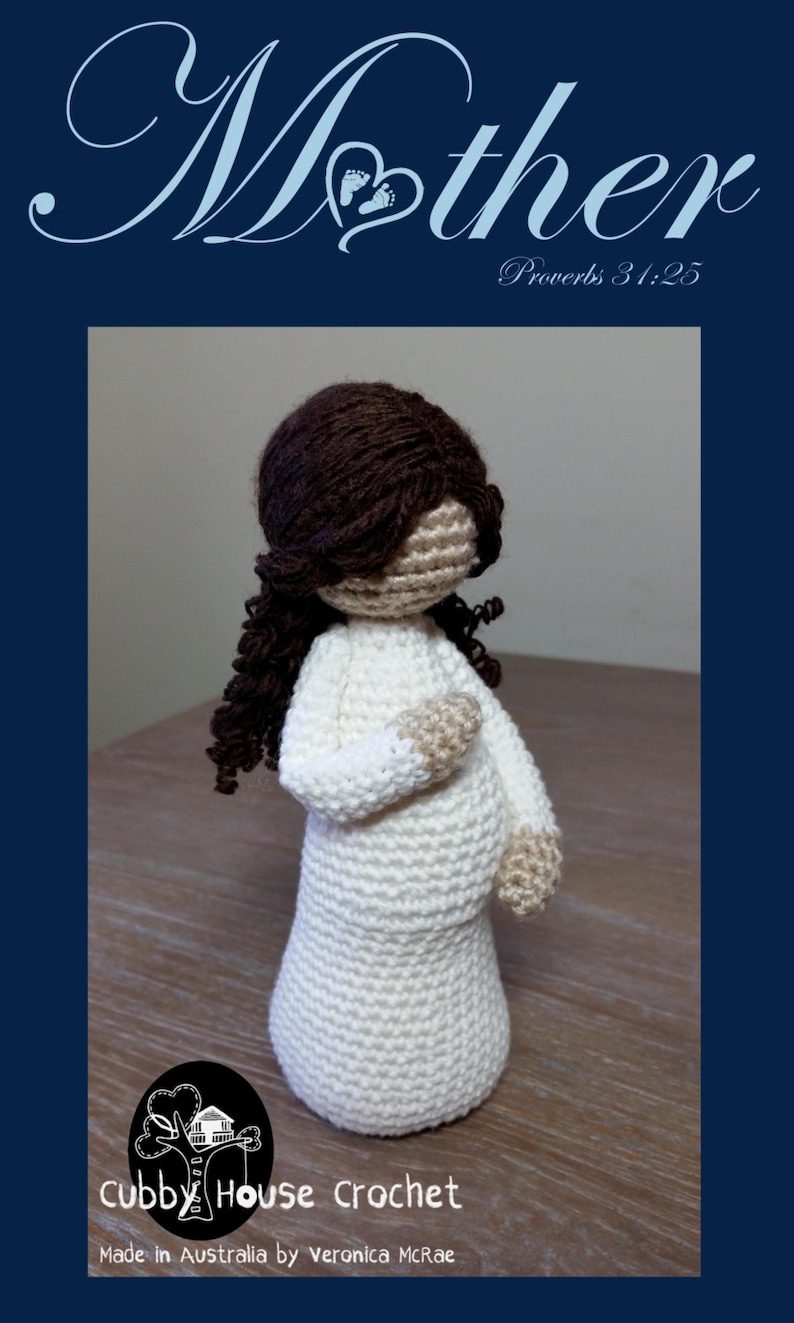 May include: Crocheted doll of a pregnant woman with brown hair. The doll is wearing a white dress and has a light brown complexion. The doll is standing on a wooden surface. The text "Mother" is written in cursive above the doll. The text "Proverbs 31:25" is written below the doll. The text "Cubby House Crochet" is written below the doll. The text "Made in Australia by Veronica McRae" is written below the doll.