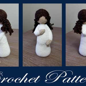 May include: Crochet pattern for a pregnant woman doll with brown hair. The doll is wearing a white dress and is standing on a wooden surface. The pattern is called "Mother" and is made by Cubby House Crochet.