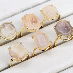 May include: Six gold rings with different shaped agate stones. The rings are displayed on a white surface.