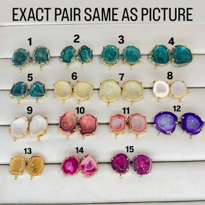 May include: Fifteen pairs of agate earrings displayed on a white background. Each pair is numbered 1 through 15. The earrings are various colors, including green, white, pink, and purple.