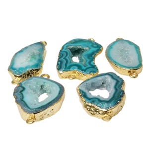 May include: Five teal and gold agate stone pendants with a hole for stringing. The stones are all different shapes and sizes, but they all have a similar pattern of white and teal agate.