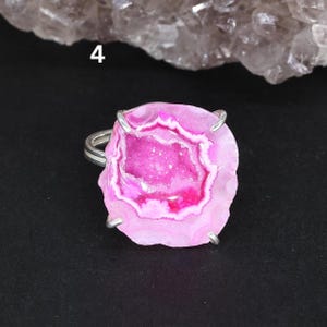 May include: A pink agate geode ring with a silver setting. The geode has a natural crystal formation with a pink and white colour scheme.