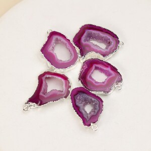 May include: Five irregular, magenta-colored agate slice pendants with silver-toned metal edges. Each pendant features a central hollow geode opening with crystalline textures and small metal loops attached to the sides for jewelry assembly.