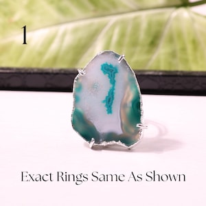 May include: A silver-toned ring featuring a polished agate stone. The stone has a white center with teal and green bands and a silver-colored edge. The text "Exact Rings Same As Shown" is at the bottom.