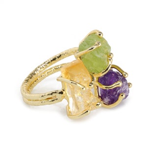 Peut inclure: Bague en or avec trois pierres précieuses brutes : une péridot verte, une citrine jaune et une améthyste violette.