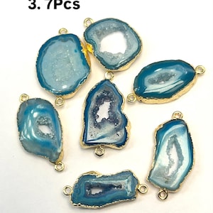 Puede incluir: Siete colgantes de piedra de ágata azul con detalles en metal dorado. Cada colgante tiene una forma única y presenta una formación de cristal natural.