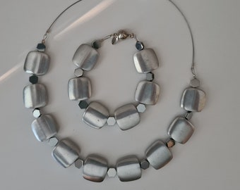 Set composed of necklace and bracelet in recycled aluminium, geometric, contemporary. Convenient magnetic closure.