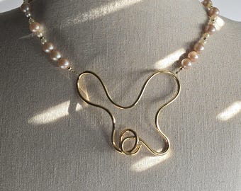 Modern pearl and gold-plated brass necklace. Hug symbol - Statement necklace. Elegant and stylish. Contemporary design. Gift idea.