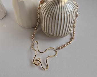Modern pearl and gold-plated brass necklace. Hug symbol - Statement necklace. Elegant and stylish. Contemporary design. Gift idea.