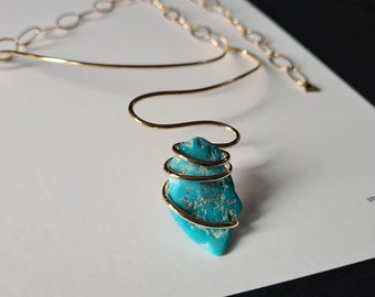 A rough Turquoise stone embraced by a golden brass thread. Sculptural and unique! Elegant and extravagant.