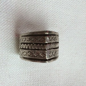 May include: A silver ring featuring intricate geometric designs and a small, clear stone.