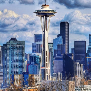 May include: A view of the Space Needle in Seattle, Washington, with a cloudy sky and a cityscape in the background.
