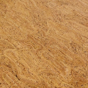May include: Close-up of a textured cork surface. The natural material features a light brown color with darker speckles and a wavy, layered pattern. The design resembles the grain of wood.