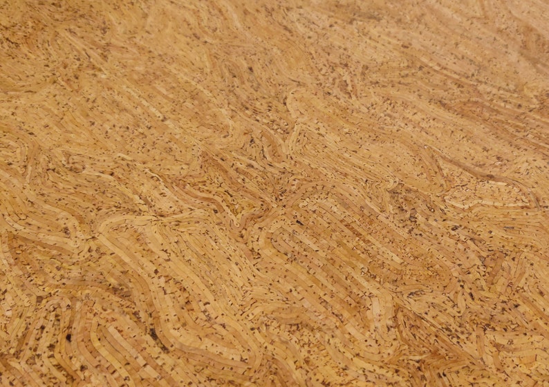 May include: Close-up of a textured cork surface. The natural material features a light brown color with darker speckles and a wavy, layered pattern. The design resembles the grain of wood.