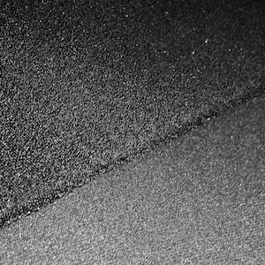 Może przedstawiać: Zbliżenie na dwa różne czarne materiały o fakturowanej powierzchni. Materiał na górze ma drobniejszą fakturę niż materiał na dole.