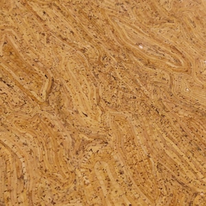 May include: Close-up of a textured, light brown cork surface. The cork has a layered, wavy pattern with darker specks throughout. The design resembles a topographical map or the rings of a tree.