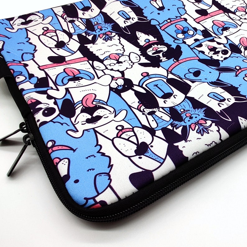 May include: A laptop sleeve with a colorful cartoon design featuring various animals, primarily dogs, in blue, pink, black, and white. The sleeve has a black zipper.