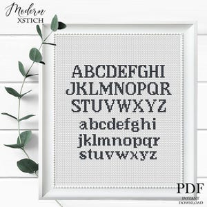 May include: A framed cross-stitch alphabet sampler in black thread on white fabric. The uppercase and lowercase letters are displayed in a classic font. The words "Modern XSTICH" are in the upper left corner. The words "PDF INSTANT DOWNLOAD" are in the lower right corner.