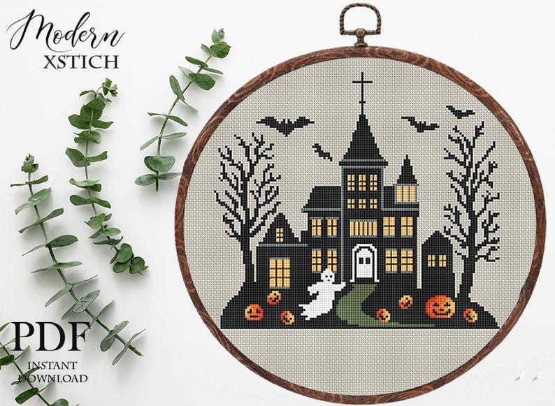 May include: Cross-stitch pattern featuring a spooky, black silhouette of a haunted house with glowing windows, bats flying overhead, and a ghost. The pattern is framed in a wooden hoop and includes the text "Modern Xstitch".