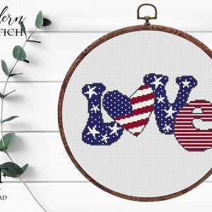 May include: A cross-stitch design in a wooden hoop features the word "LOVE" with the letters filled with the American flag's stars and stripes. The design is on a white background. The text "Modern XSTICH" and "PDF INSTANT DOWNLOAD" are also visible.