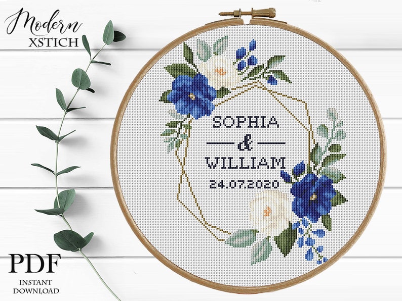 Pu&ograve; includere: Schema di punto croce con una ghirlanda floreale con fiori blu e bianchi, una cornice geometrica dorata e il testo "Sophia & William 24.07.2020".