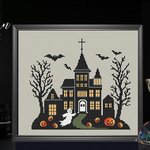 May include: A black and white cross stitch pattern of a spooky Halloween house with a ghost, bats, and pumpkins. The pattern is framed and ready to be stitched.