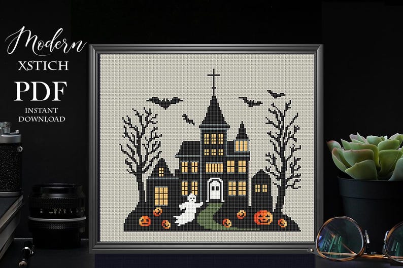 May include: A black and white cross stitch pattern of a spooky Halloween house with a ghost, bats, and pumpkins. The pattern is framed and ready to be stitched.