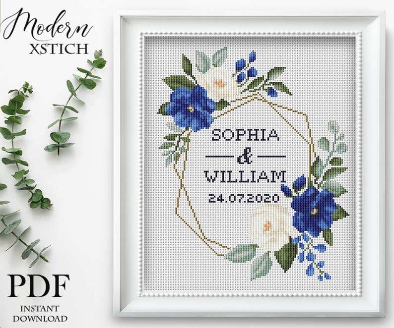 Pu&ograve; includere: Schema di punto croce con una ghirlanda di fiori blu e bianchi, una cornice geometrica dorata e il testo "Sophia & William 24.07.2020".