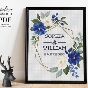 Pu&ograve; includere: Schema di punto croce con una ghirlanda di fiori blu e bianchi, una cornice geometrica dorata e il testo "Sophia & William 24.07.2020".
