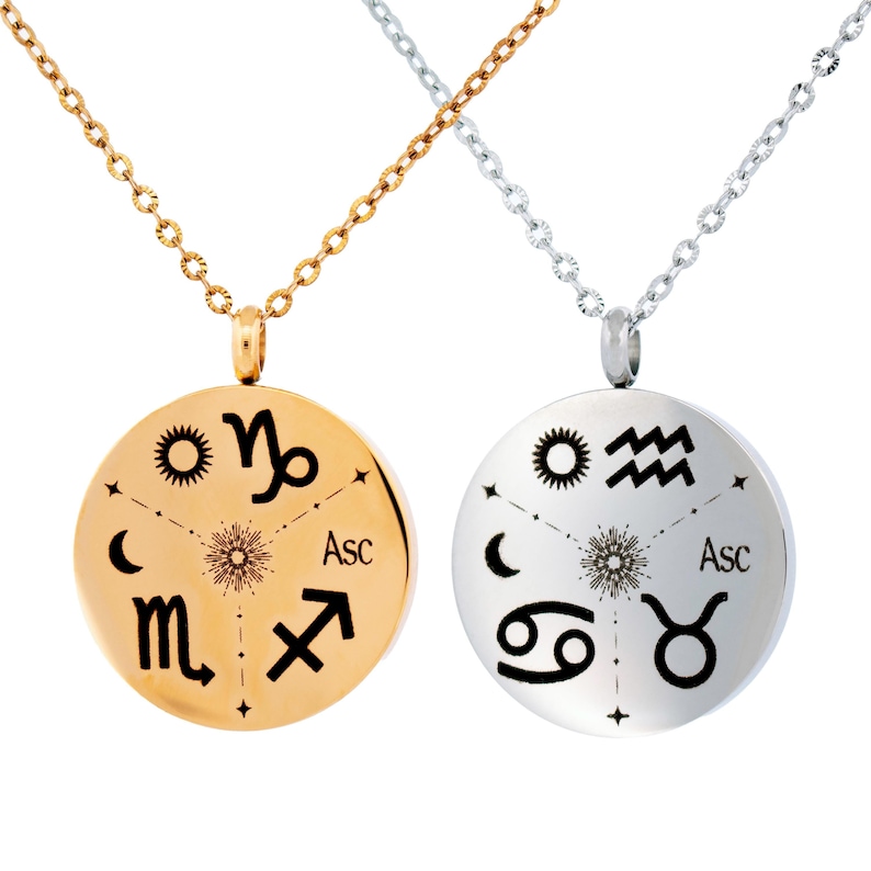 May include: Two round pendant necklaces, one gold-toned and one silver-toned, each featuring a central sunburst design surrounded by four black engraved zodiac symbols, a crescent moon, and the text Asc, suspended on matching metal link chains.