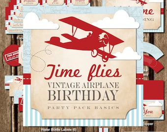 May include: Vintage airplane birthday party printable pack with red and blue accents. Includes a banner, water bottle labels, party signs, napkin rings, and Hershey's Kiss circles.