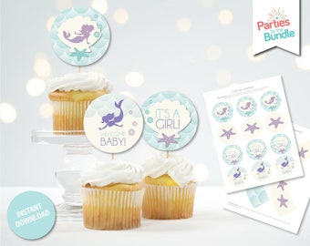 May include: Printable cupcake toppers featuring a mermaid, seashells, and the text "It's a Girl!" and "Welcome Baby!" in purple and white text on a light blue background.